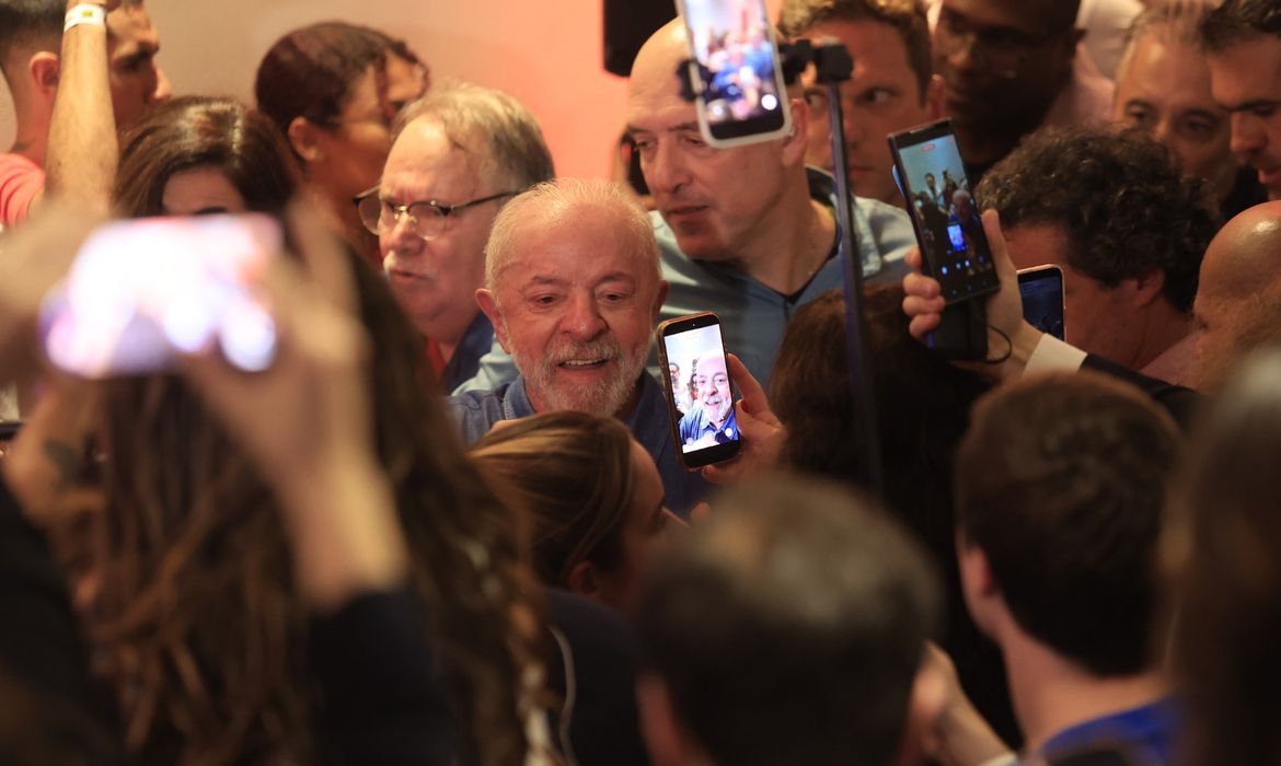 Lula cercado por eleitores com celulares, que registram sua presença após a reeleição em São Paulo.